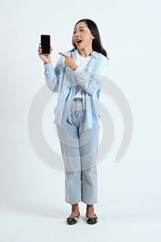full leght shoot of happy asian indonesian woman holding phone and showing blank screen on isolated background photo
