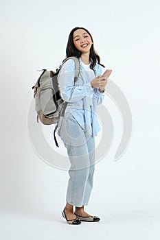 full leght shoot of happy asian Indonesian woman wearing casual attire, holding smartphone and backpack on isolated background