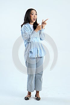 full leght shoot of happy asian Indonesian woman wearing casual attire, pointing finger on isolated background
