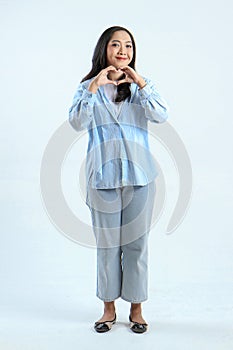 full leght shoot of happy asian Indonesian woman wearing casual attire, showing love sign gesture on isolated background