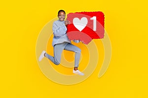 Full legth photo of young popular lady jumping air holding big red heart social media isolated on yellow color