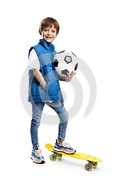 Full lengh image of a smiling little boy with backpack holding soccer ball on white background. Back to School.
