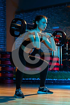 Full lengh shot of sporty young woman make squat exercise with barbell in gym. Health and Sport concept. photo