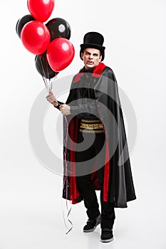 Full-lenght Portrait of handsome caucasian Vampire in black and red halloween costume.