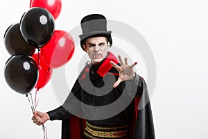 Full-lenght Portrait of handsome caucasian Vampire in black and red halloween costume.