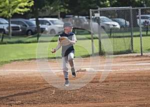 Full length Action photo of a Little League baseball pitcher throwing a pitch