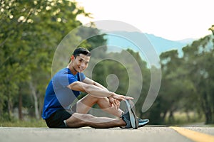 Full length of active sportsman in fitness clothes stretching leg, preparing for morning workout in the public park