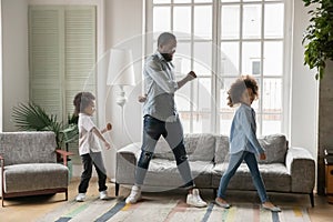 Full length African American father with kids dancing at home