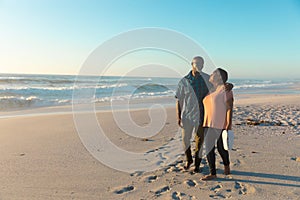 Full length of african american senior couple walking at beach against sky with copy space