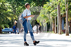 Full length attractive young african woman walking with bag and mobile phone