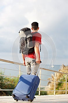 Full length backpacker walking away backpack and suitcase