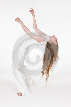 Full length barefoot young woman with eyes closed having fun while bending over backwards on white