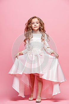 Full length of beautiful little girl in dress standing and posing over white background photo