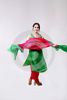 Full Length Of An Beautiful Model In Red And Green Salwar Kameez With Dupatta Standing Over Grey Background photo