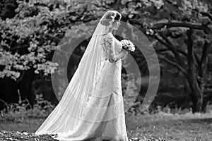 Full length of beautiful sensual young retro vintage bride in long white wedding dress holding bouquet outdoor.