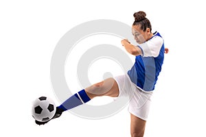 Full length of biracial young female soccer player kicking soccer ball while playing soccer