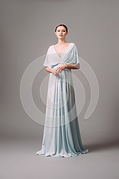 Full-length blue bridesmaid dress with flutter sleeves. Effortless festive summer look.