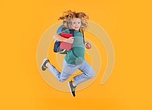 Full length body of little school kid jumping having fun isolated yellow color background. Crazy school boy jump.