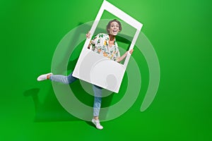 Full length body photo of attractive young girl holding paper photozone snapshot social media frame  on green