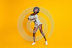 Full length body size photo of black skinned woman in shorts top dancing wering star sunglass isolated on vivid yellow