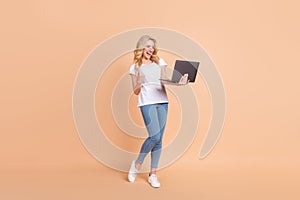 Full length body size photo blonde woman gesturing like winner keeping laptop isolated pastel beige color background