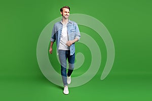 Full length body size photo of confident man walking forward looking blank space isolated bright green color background