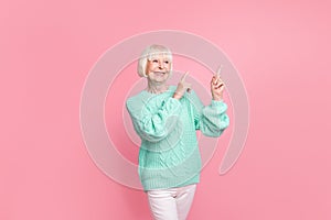Full length body size photo of happy grandmother blonde hair pointing at blank space smiling isolated on pastel pink