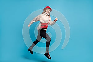 Full length body size photo model in red hat jumping high running fast smiling isolated vivid blue color background