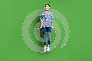 Full length body size photo of young guy jumping high smiling happy isolated bright green color background