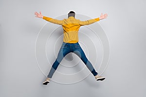 Full length body size rear back behind view of attractive free man jumping having fun isolated over grey color