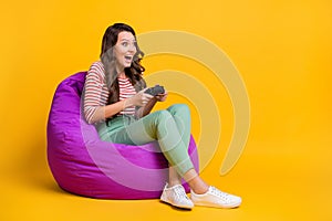 Full length body size side profile photo of crazy girl in chair keeping game console isolated on vivid yellow color