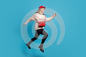 Full length body size side profile photo model in red hat jumping high running on sale isolated vivid blue color