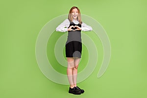 Full length body size view of affectionate cheerful amazed girl showing heart sign  over green color background