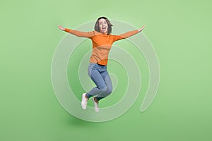 Full length body size view of attractive cheerful funky girl jumping having fun good mood isolated over green color