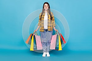 Full length body size view of attractive cheerful girl holding new things buyings isolated over bright blue color photo