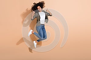Full length body size view of attractive cheerful girl jumping showing thumbup advert isolated over beige pastel color