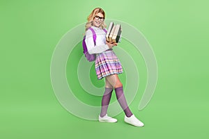 Full length body size view of attractive cheerful girl learner holding book lecture lesson isolated over green color