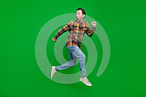 Full length body size view of attractive funky amazed man jumping running away isolated over bright green color