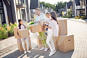 Full length body size view of four cheery family brother sister moving to new apartment carrying packages in cottage