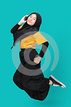 Full length body size view of Happy Young Asian teenager girl jumping and using phone with a smile on her face. Happiness,