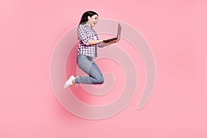 Full length body size view of lovely cheerful amazed girl jumping using laptop isolated over pink pastel color