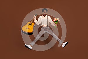 Full length body size view of nice cheerful funky guy jumping holding guitar tulips sale isolated over brown color
