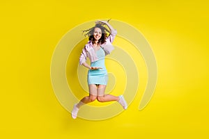 Full length body size view of pretty cheerful wavy-haired girl jumping showing large size isolated over bright yellow