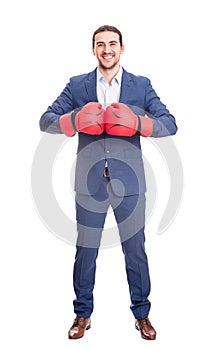 Full length businessman in suit with boxing gloves stands ready in a fighting stance, punching his fists. Business person self