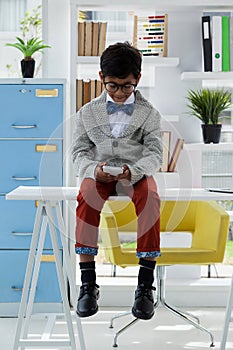 Full length of businessman using smart phone while sitting on desk