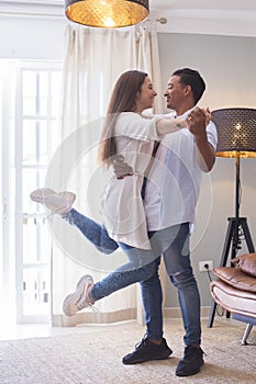 .Full length of carefree young couple dancing at home together