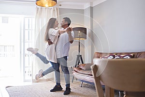.Full length of carefree young couple dancing at home together