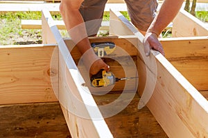 Full length carpenter drilling wood at construction site