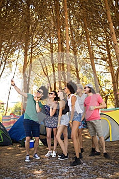 Full length of cheerful friends taking selfie at campsite