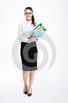 Full length of cheerful young businesswoman standing and holding folders